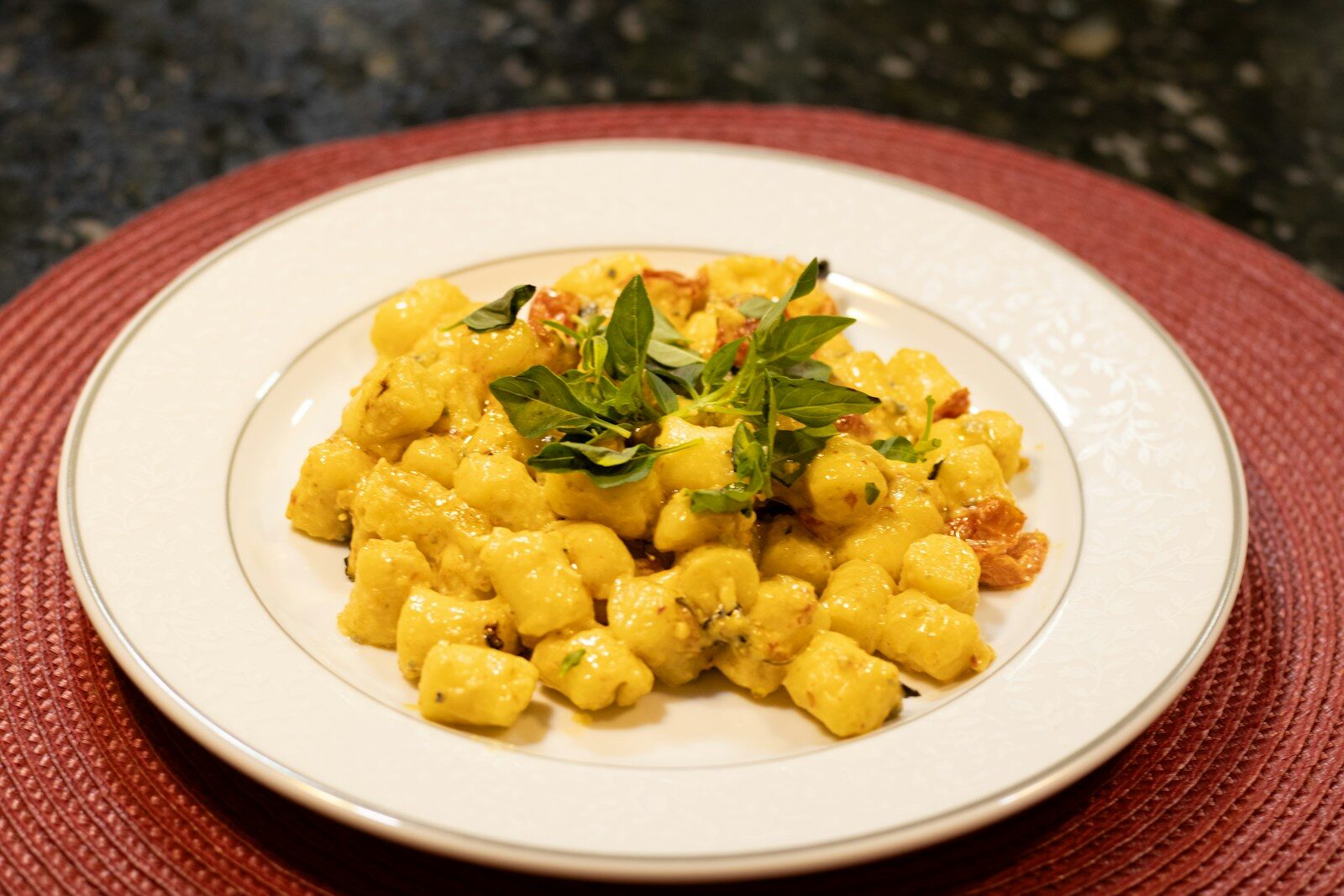 Photo by Leandro Rossi Gnocchi with sauce and fresh basil served on a plate.